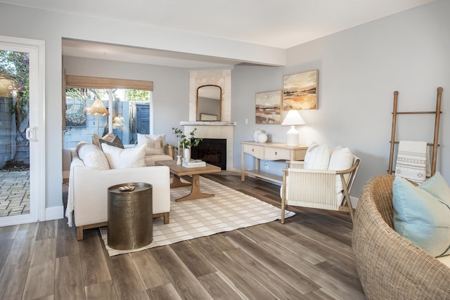 living room featuring wood-type flooring, a tile fireplace, and plenty of natural light