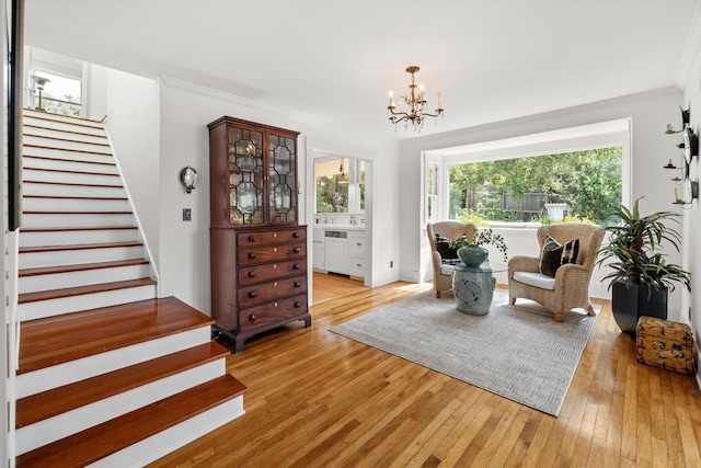 sitting room featuring light hardwood / wood-style floors, ornamental molding, and an inviting chandelier