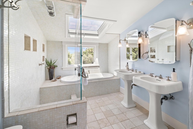 bathroom featuring tiled tub, tile patterned floors, double sink, and lofted ceiling with skylight