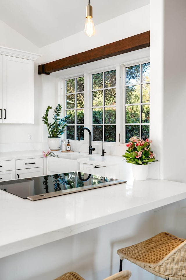 kitchen featuring white cabinetry, pendant lighting, black electric stovetop, and lofted ceiling