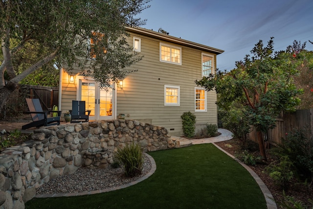 back house at dusk with a lawn