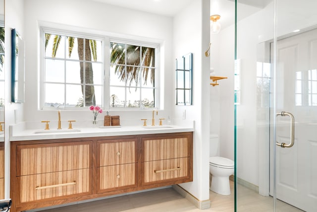 bathroom with vanity, toilet, and a shower with door