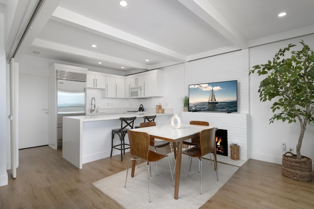 1508 Miramar, Santa Barbara, CA 93108 - dining space featuring a brick fireplace, sink, light hardwood / wood-style flooring, and beamed ceiling