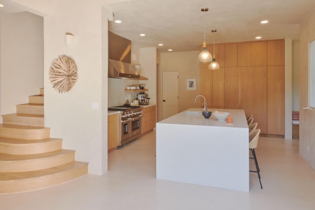 kitchen with double oven range, a kitchen island with sink, pendant lighting, and range hood