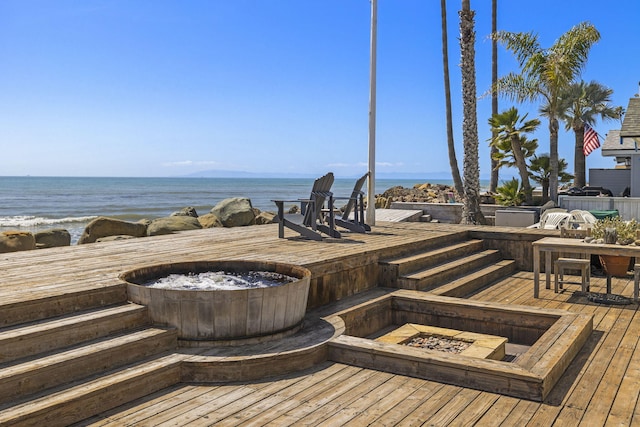 wooden deck featuring a water view and a fire pit