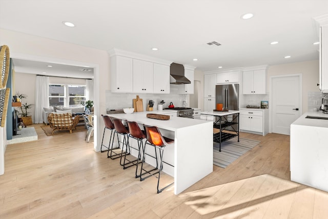 kitchen with tasteful backsplash, a kitchen bar, white cabinetry, light wood-type flooring, and premium appliances