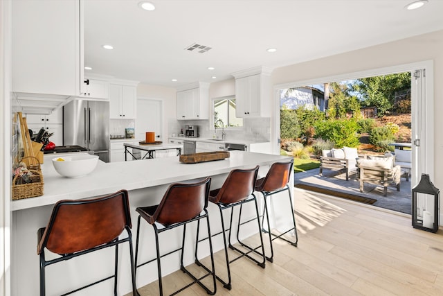 kitchen featuring kitchen peninsula, appliances with stainless steel finishes, a kitchen breakfast bar, white cabinets, and sink