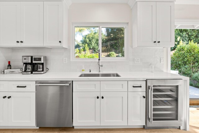 kitchen with white cabinets, stainless steel dishwasher, beverage cooler, and backsplash