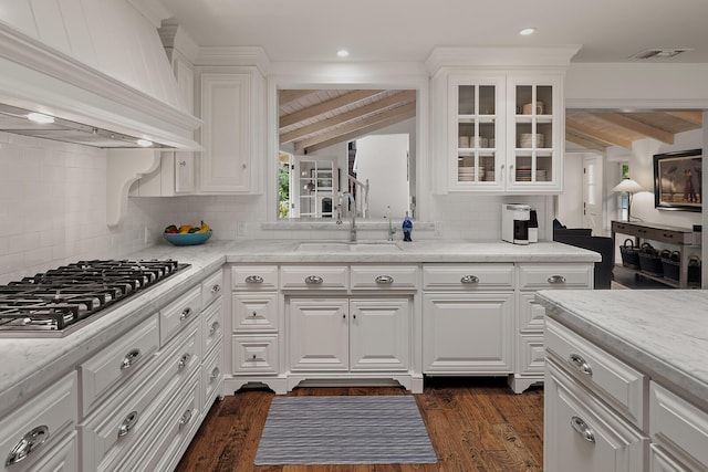 kitchen with tasteful backsplash, white cabinetry, stainless steel gas cooktop, and custom exhaust hood