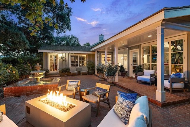 patio terrace at dusk featuring an outbuilding and an outdoor living space with a fire pit