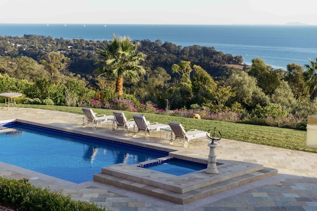 view of pool with a water view, a patio area, an in ground hot tub, and a lawn