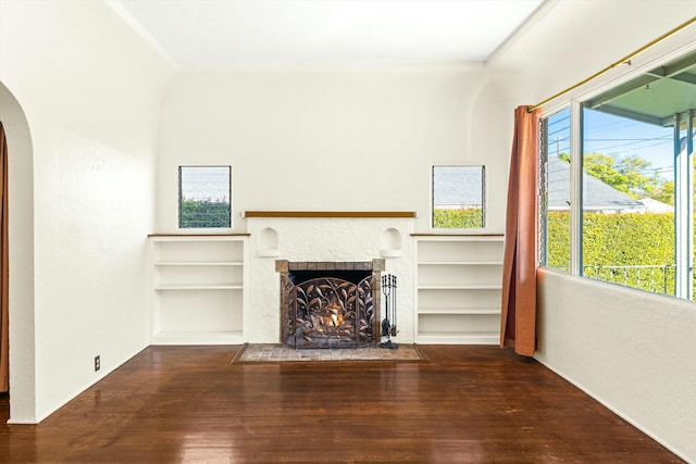 unfurnished living room with plenty of natural light, built in shelves, and a fireplace