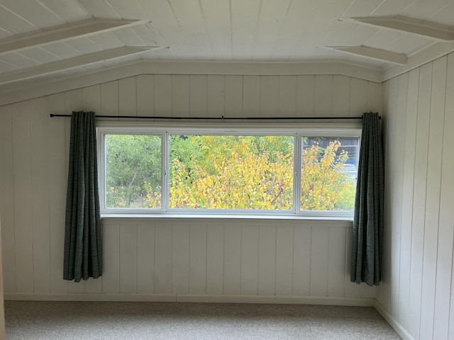 unfurnished room featuring a wealth of natural light, carpet flooring, and lofted ceiling with beams