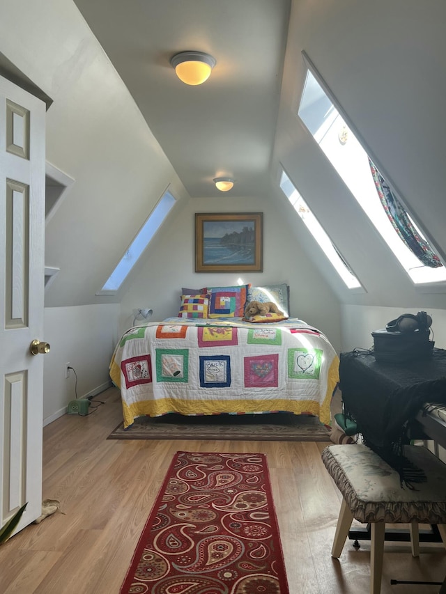 bedroom with vaulted ceiling with skylight, multiple windows, and light hardwood / wood-style flooring