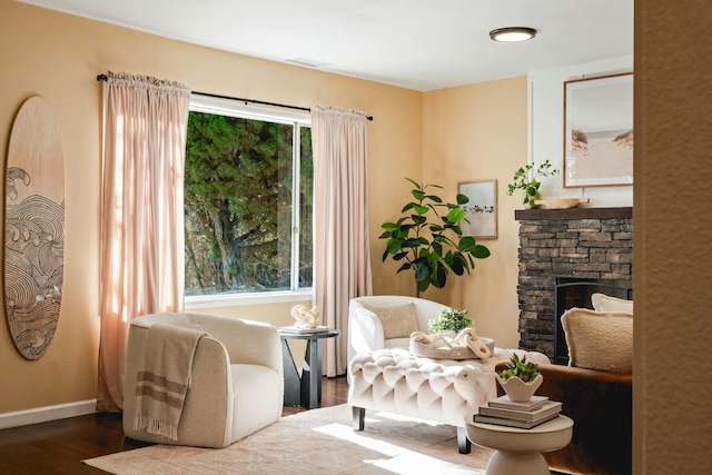 living area featuring a stone fireplace and hardwood / wood-style flooring