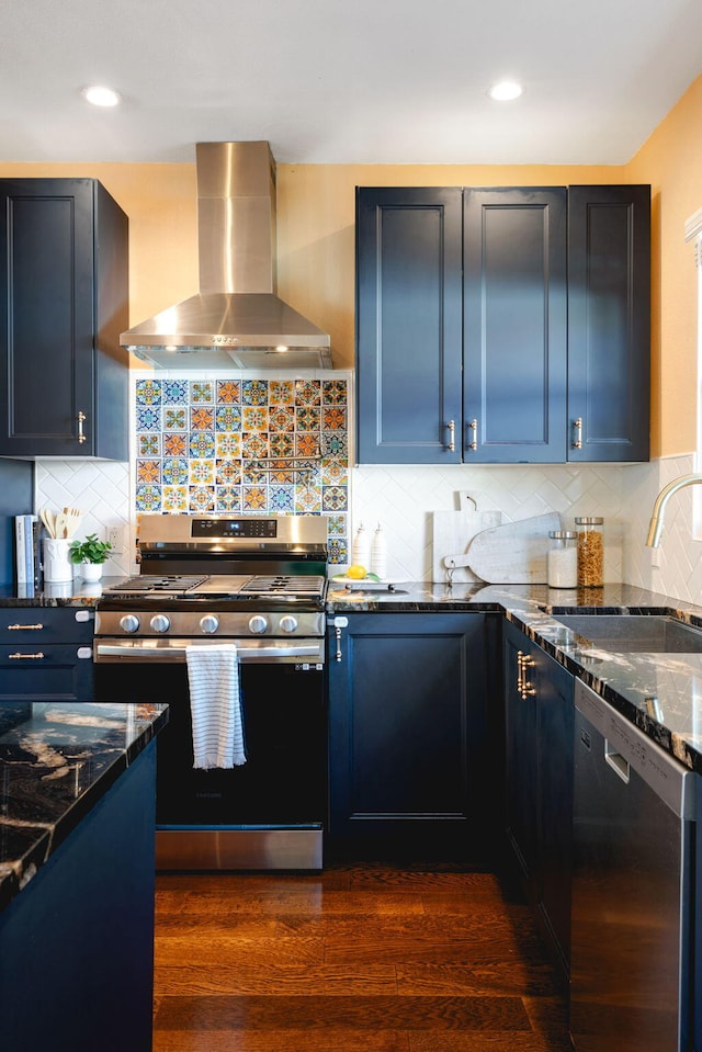 kitchen featuring dark wood-type flooring, sink, appliances with stainless steel finishes, wall chimney range hood, and backsplash