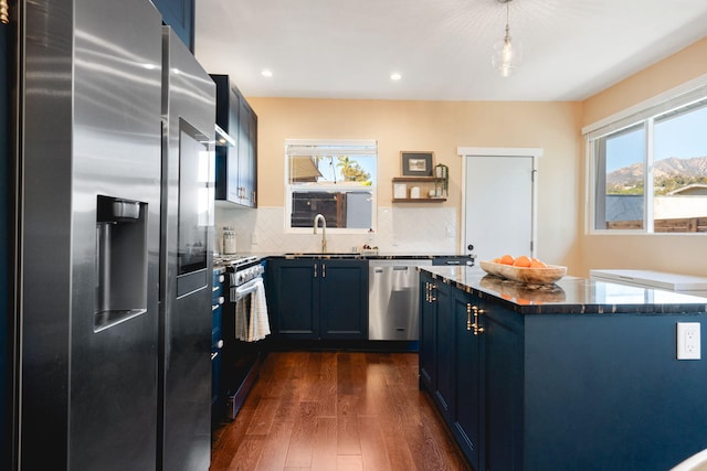 kitchen featuring blue cabinets, sink, hanging light fixtures, and appliances with stainless steel finishes