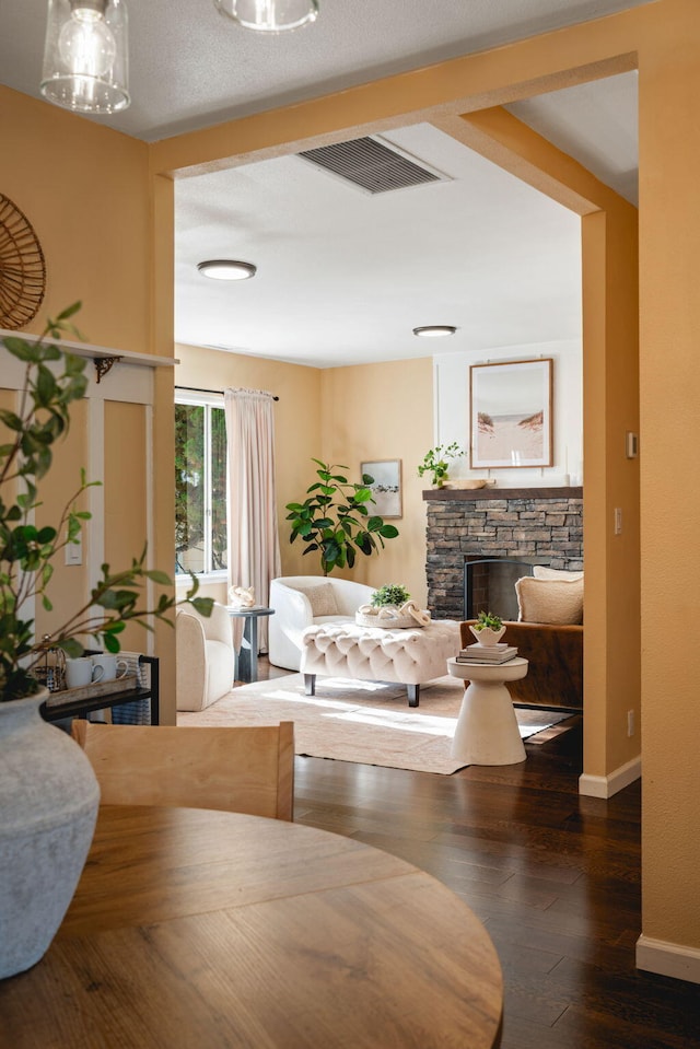 dining space with hardwood / wood-style flooring and a stone fireplace