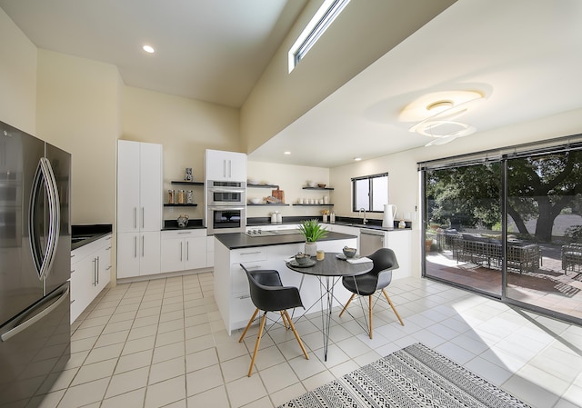 kitchen featuring appliances with stainless steel finishes, sink, light tile patterned floors, and white cabinets