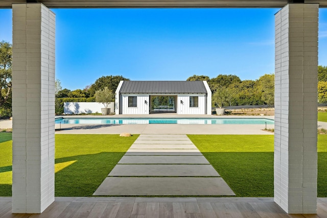 view of swimming pool featuring an outbuilding and a lawn