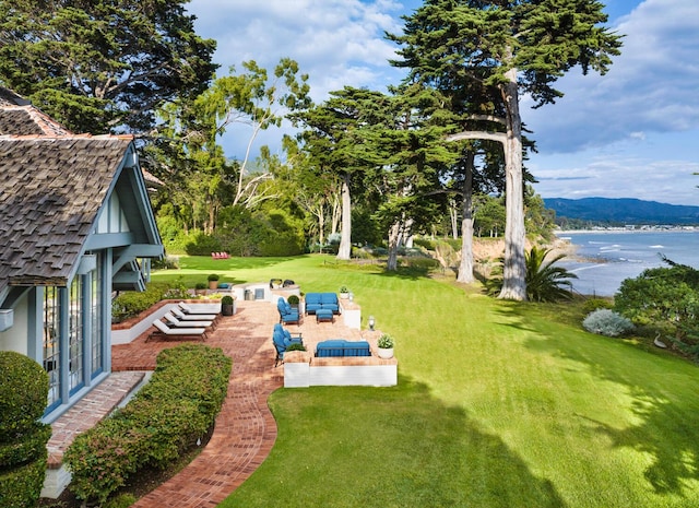 view of yard with an outdoor living space, a water and mountain view, a patio area, and french doors