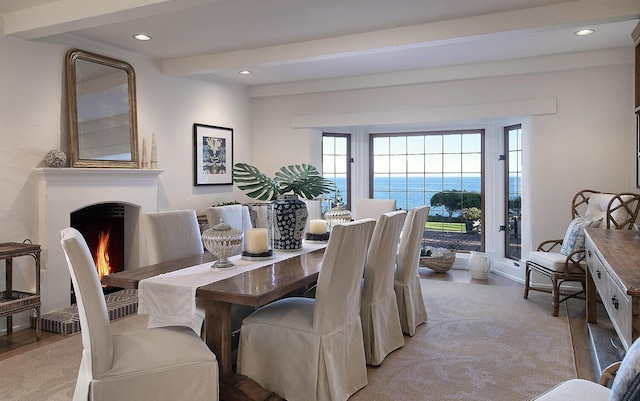 carpeted dining area featuring a water view and beam ceiling