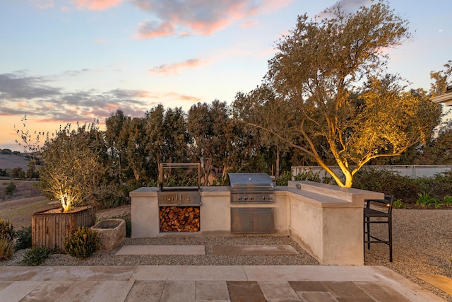 view of patio / terrace with exterior kitchen, an outdoor bar, a grill, and fence