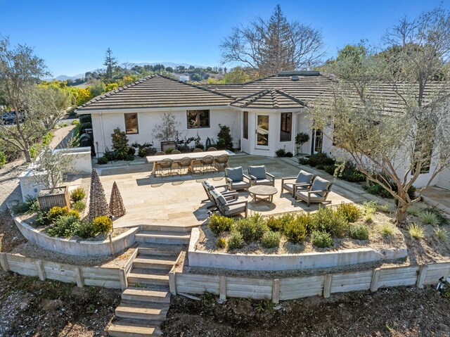 rear view of house with a tile roof, a patio, and an outdoor hangout area