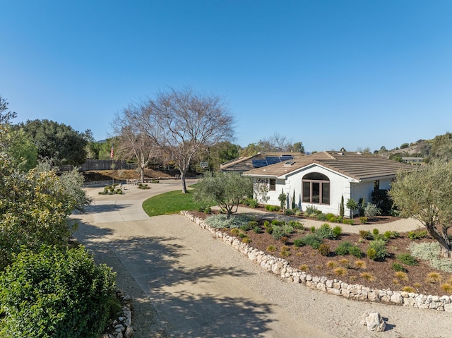 view of front of home with roof mounted solar panels, driveway, a tiled roof, and stucco siding