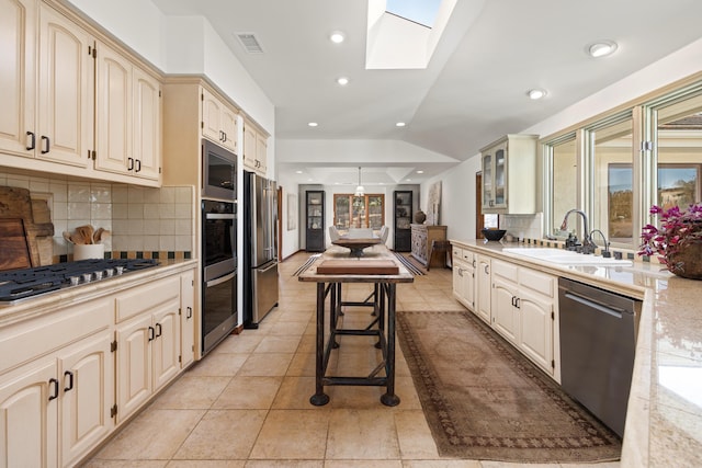 kitchen featuring visible vents, lofted ceiling with skylight, glass insert cabinets, stainless steel appliances, and a sink