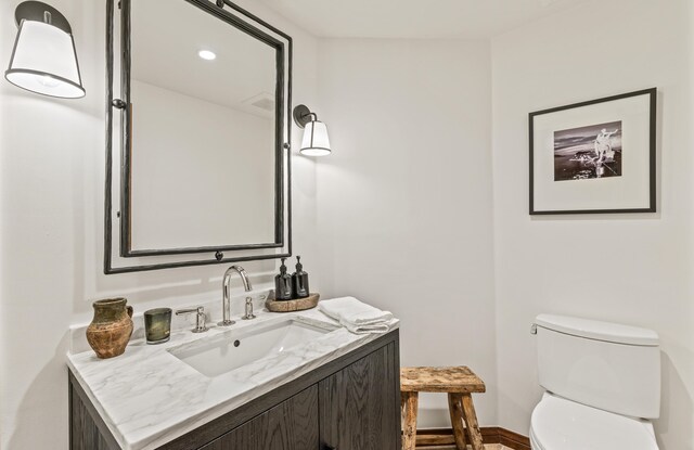 bathroom with toilet, vanity, and recessed lighting