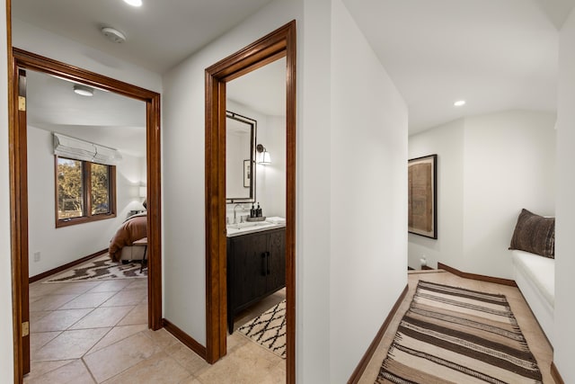 hall featuring baseboards, light tile patterned floors, a sink, and recessed lighting