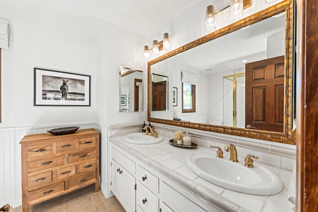 full bathroom with double vanity, wainscoting, a sink, and a shower stall