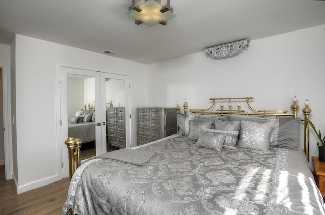 bedroom featuring french doors, hardwood / wood-style floors, and a closet