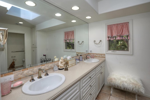 bathroom featuring a skylight, backsplash, tile patterned flooring, vanity, and toilet