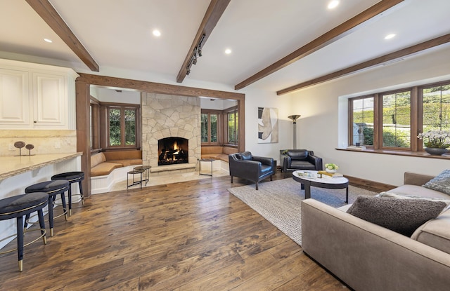 living room featuring dark hardwood / wood-style flooring, beam ceiling, a fireplace, and a healthy amount of sunlight