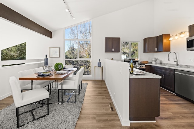 kitchen with sink, a center island, dark brown cabinets, dark hardwood / wood-style floors, and stainless steel appliances