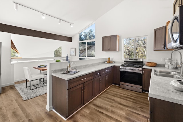 kitchen with sink, light hardwood / wood-style floors, kitchen peninsula, and appliances with stainless steel finishes