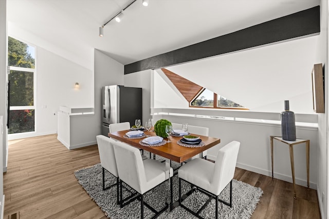 dining area featuring lofted ceiling, hardwood / wood-style floors, and track lighting