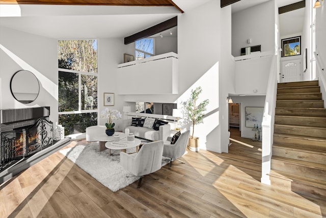 living room with beamed ceiling, hardwood / wood-style flooring, and a towering ceiling