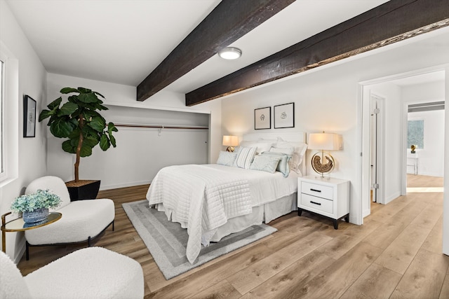 bedroom with beamed ceiling and light wood-type flooring