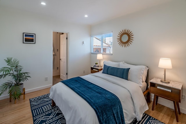 bedroom featuring ensuite bath and light hardwood / wood-style floors