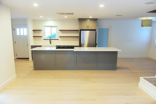 kitchen featuring light hardwood / wood-style flooring, stainless steel fridge, a kitchen island, and gray cabinetry