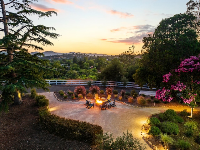 yard at dusk featuring an outdoor fire pit, a mountain view, and a patio area