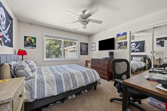 carpeted bedroom with a textured ceiling, ceiling fan, and a closet