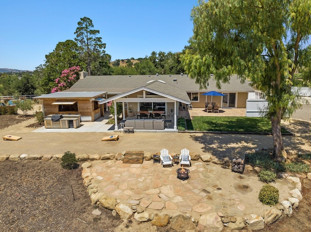 back of house featuring a patio and an outdoor living space with a fire pit