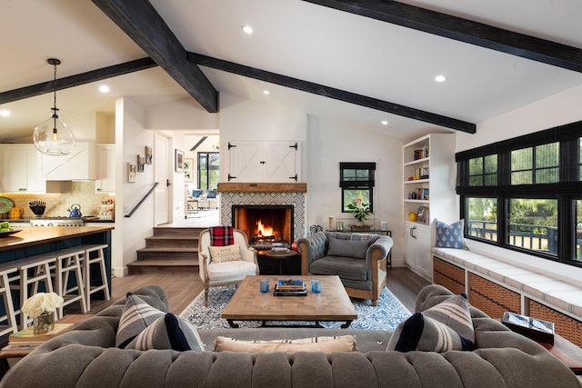 living room with a tiled fireplace, vaulted ceiling with beams, and hardwood / wood-style flooring