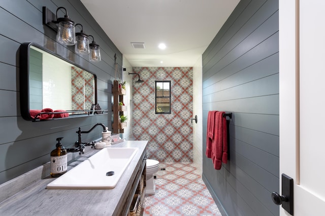 bathroom featuring toilet, vanity, and wooden walls