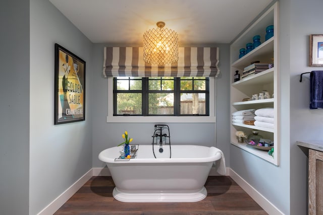 bathroom featuring wood-type flooring, a tub, an inviting chandelier, and built in shelves