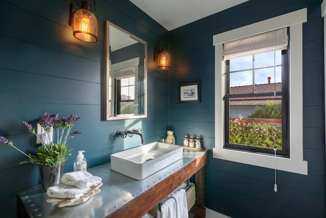 bathroom featuring sink and wood walls